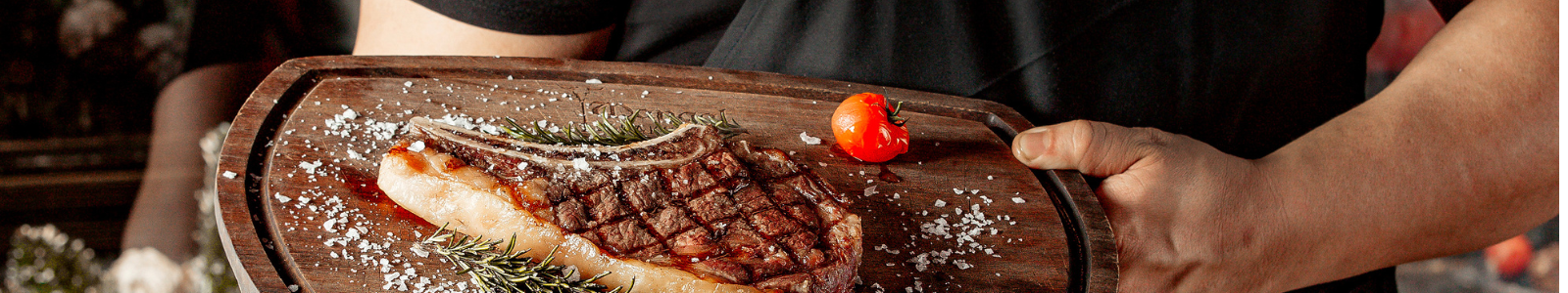 Asado argentino servido en una mesa al aire libre con vino y guarniciones.