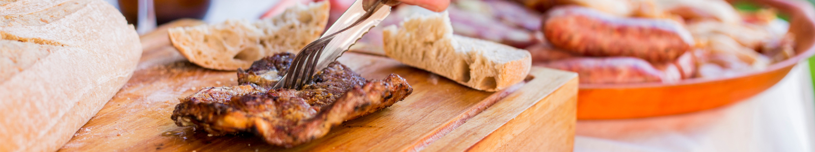 Parrilla con brasas encendidas y cortes de carne asándose.