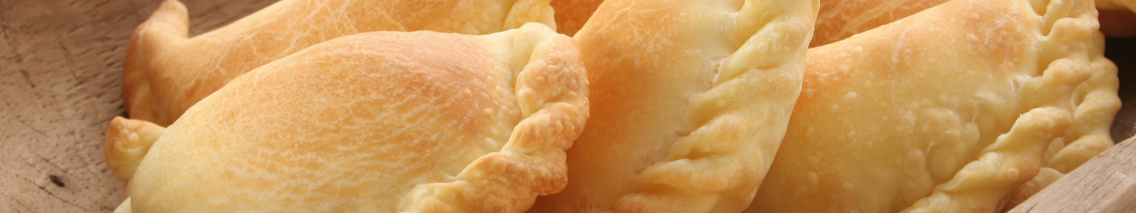 Empanadas criollas doradas saliendo del horno de barro.